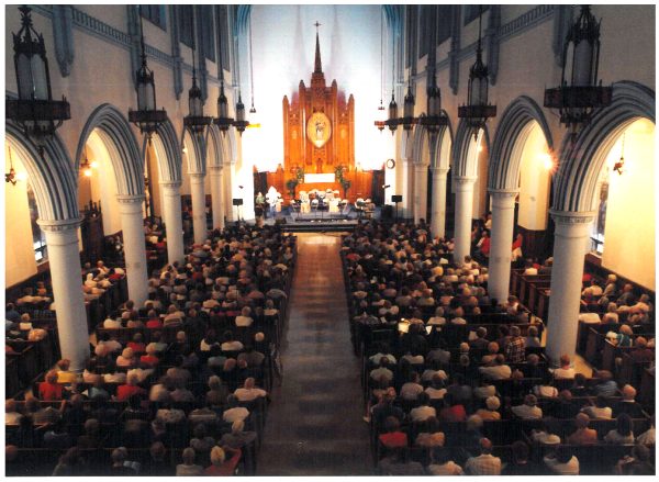 interior of church with people seated in pews and alter lit brightly